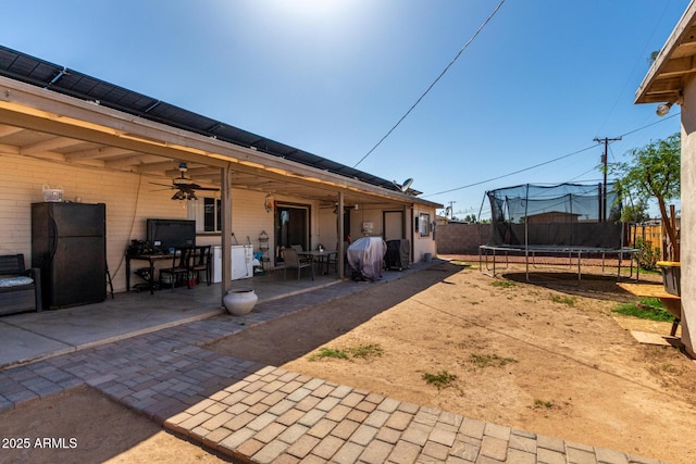 4403 N 56th Dr, Phoenix, AZ 85031 - fenced backyard with a trampoline, ceiling fan, a patio, and outdoor dining space