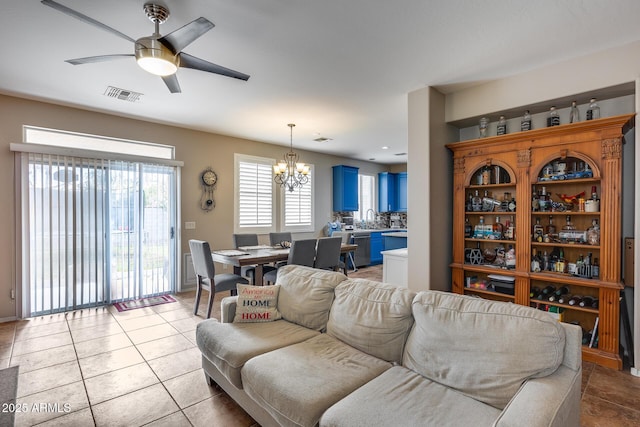 living room with light tile patterned floors, ceiling fan with notable chandelier, and sink