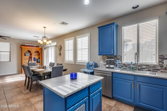 kitchen featuring blue cabinets, sink, stainless steel dishwasher, decorative light fixtures, and a kitchen island