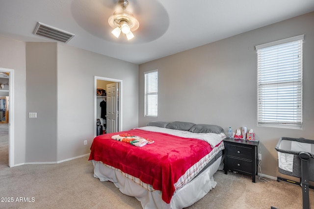 bedroom featuring light carpet, a closet, a spacious closet, and ceiling fan