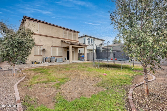 rear view of house with a yard and a trampoline