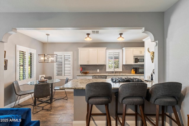 69 W Virginia Ave, Phoenix, AZ 85003 - kitchen with a sink, decorative backsplash, a breakfast bar, dark wood-style flooring, and white cabinets