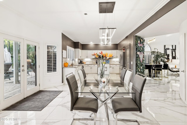 dining space featuring french doors, ornamental molding, a chandelier, and sink