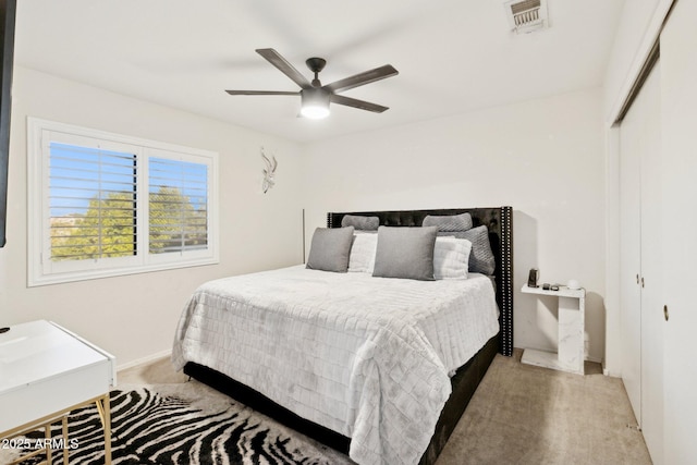 bedroom featuring light colored carpet, ceiling fan, and a closet