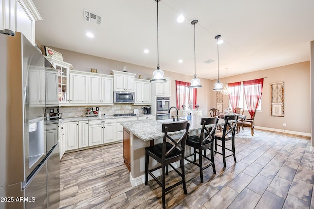 20421 W Legend Trl, Buckeye, AZ 85396 - kitchen with stainless steel appliances, a kitchen bar, backsplash, white cabinets, and light wood-style flooring