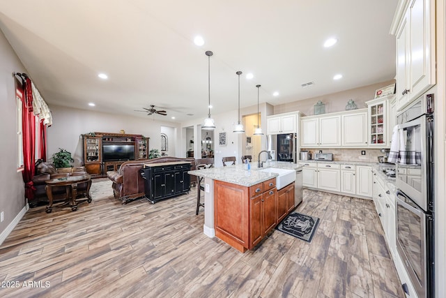 20421 W Legend Trl, Buckeye, AZ 85396 - kitchen with a sink, open floor plan, ceiling fan, light wood-style floors, and a breakfast bar area