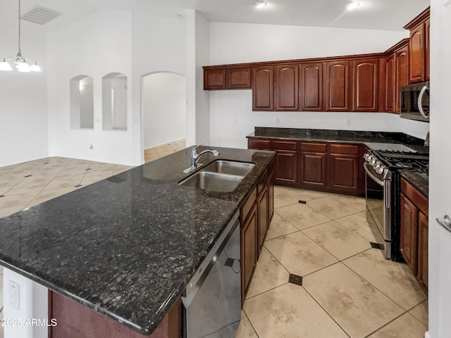 kitchen with an island with sink, vaulted ceiling, appliances with stainless steel finishes, and sink