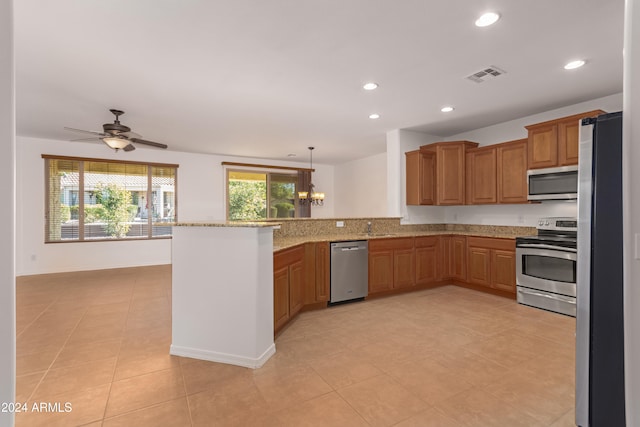 kitchen with stainless steel appliances, kitchen peninsula, decorative light fixtures, light tile patterned floors, and ceiling fan with notable chandelier