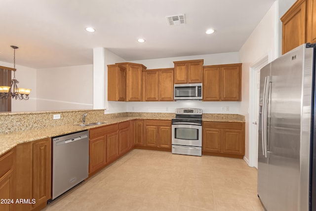 kitchen featuring sink, hanging light fixtures, light stone counters, a chandelier, and appliances with stainless steel finishes