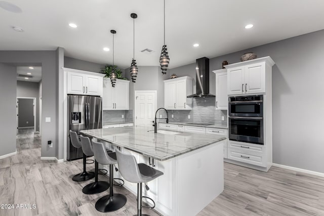 kitchen with wall chimney range hood, hanging light fixtures, sink, appliances with stainless steel finishes, and a large island