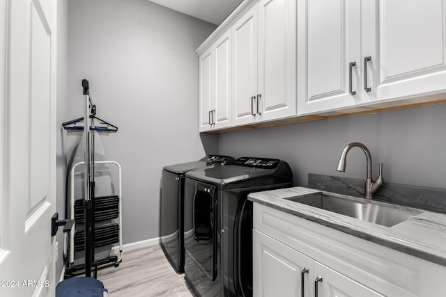 laundry area featuring cabinets, sink, light hardwood / wood-style flooring, and washing machine and clothes dryer