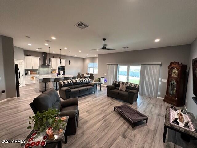 living room with light hardwood / wood-style flooring and ceiling fan