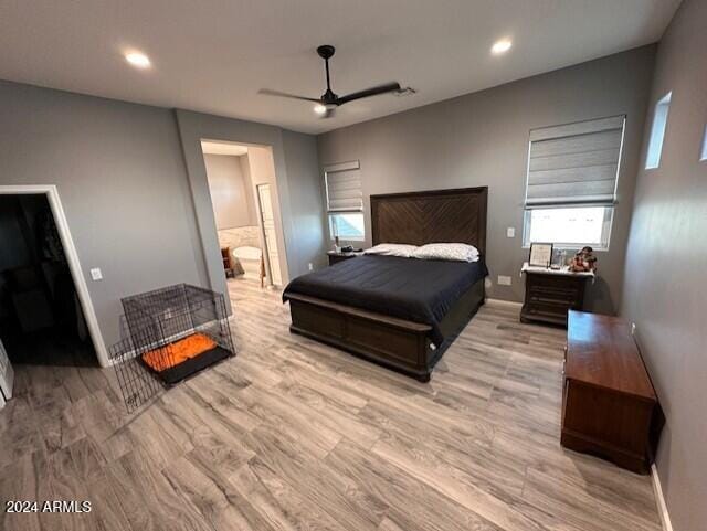 bedroom with ensuite bathroom, ceiling fan, light hardwood / wood-style floors, and a walk in closet