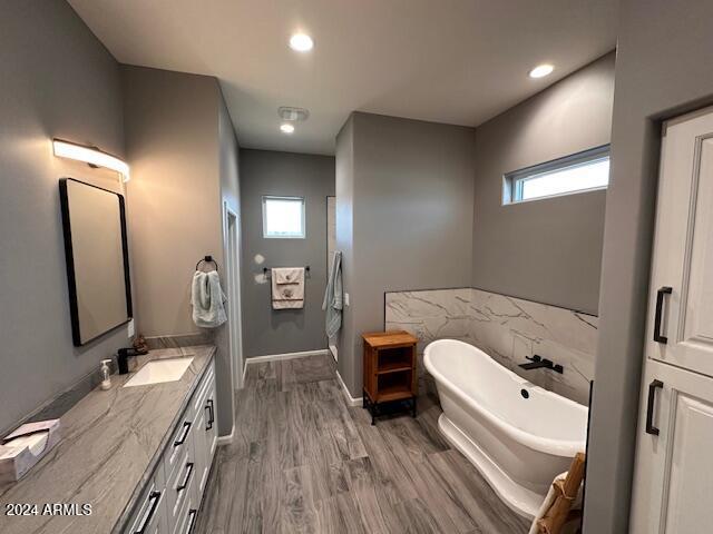 bathroom with vanity, wood-type flooring, and a tub to relax in