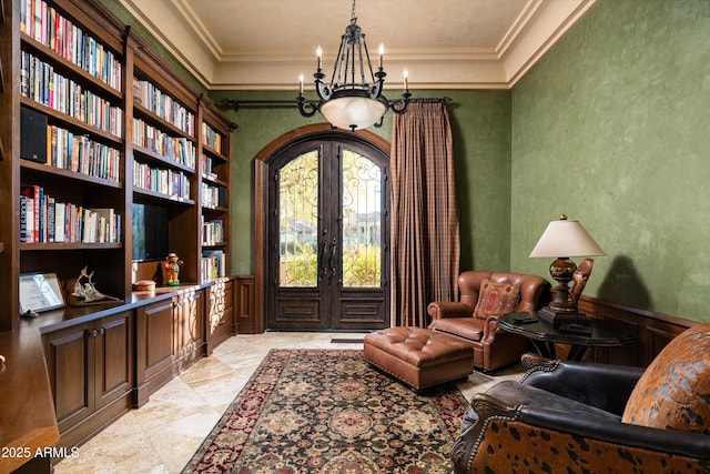 sitting room featuring french doors, crown molding, a chandelier, and built in features