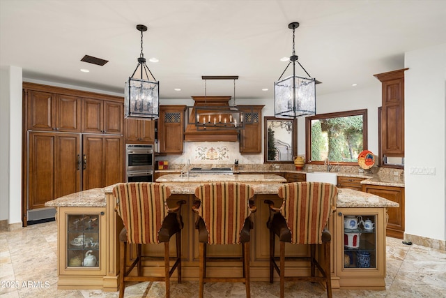 kitchen featuring a large island, backsplash, and light stone counters