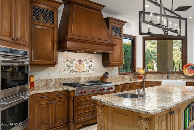 kitchen featuring sink, hanging light fixtures, a center island with sink, custom range hood, and stainless steel appliances