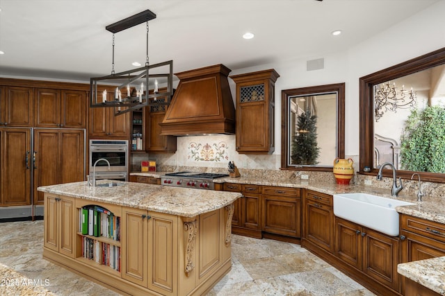 kitchen featuring sink, custom exhaust hood, hanging light fixtures, and a center island with sink