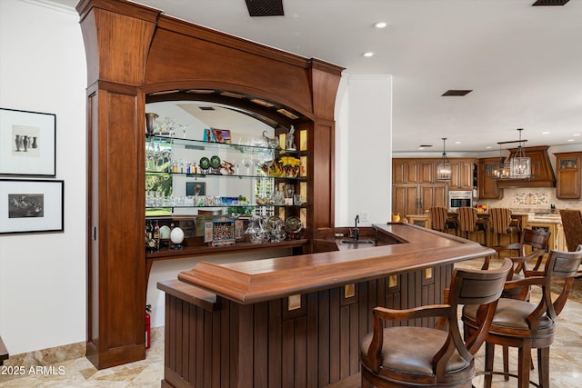 bar featuring ornamental molding, sink, decorative backsplash, and decorative light fixtures