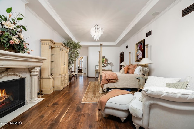 bedroom featuring dark wood-type flooring, a high end fireplace, crown molding, and an inviting chandelier