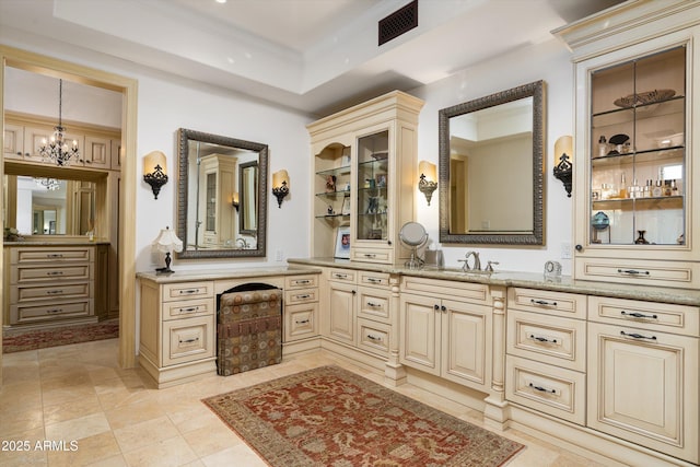 bathroom with vanity, a raised ceiling, and a chandelier