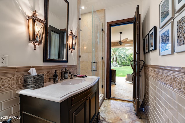 bathroom featuring tile walls, vanity, crown molding, and a shower with door