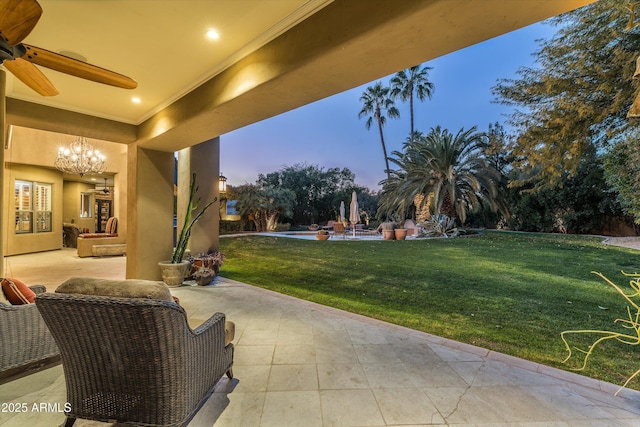 patio terrace at dusk featuring a lawn and ceiling fan