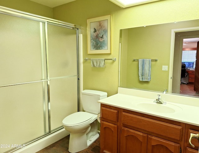 bathroom featuring hardwood / wood-style flooring, vanity, a shower with shower door, and toilet