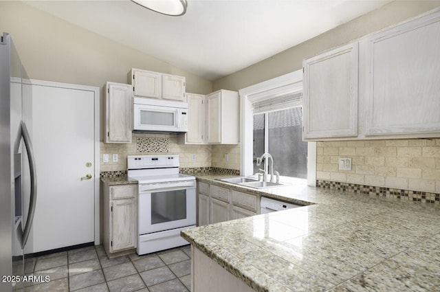 kitchen with sink, tasteful backsplash, vaulted ceiling, light tile patterned floors, and white appliances