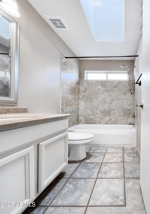 full bathroom with vanity, tiled shower / bath, and toilet