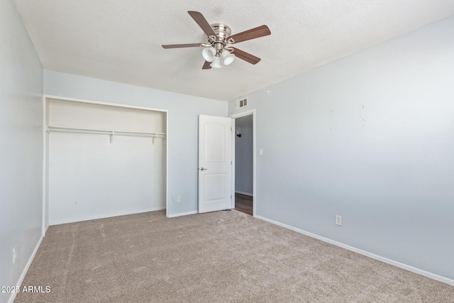 unfurnished bedroom with ceiling fan, a closet, light carpet, and a textured ceiling