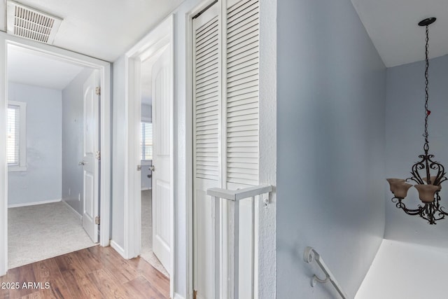 corridor with hardwood / wood-style floors and a notable chandelier