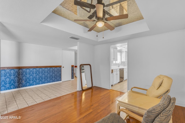 11465 N 56th St, Scottsdale, AZ 85254 - living area featuring a tray ceiling, ceiling fan, light wood-style floors, and baseboards