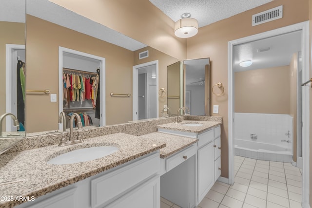 11465 N 56th St, Scottsdale, AZ 85254 - bathroom with tile patterned flooring, a spacious closet, vanity, a bath, and a textured ceiling