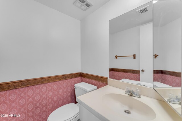 11465 N 56th St, Scottsdale, AZ 85254 - half bathroom featuring a wainscoted wall, vanity, and toilet