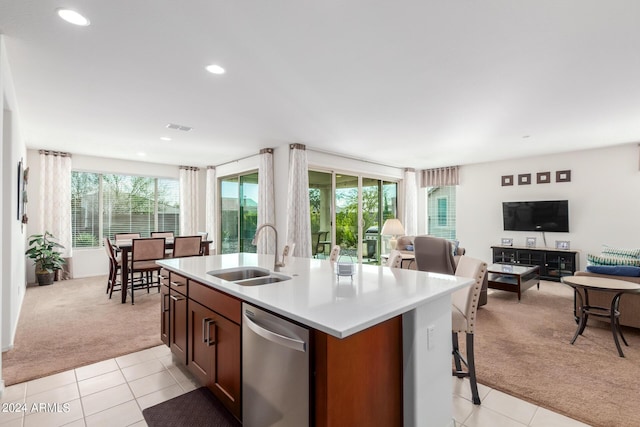 kitchen featuring stainless steel dishwasher, an island with sink, sink, and light carpet