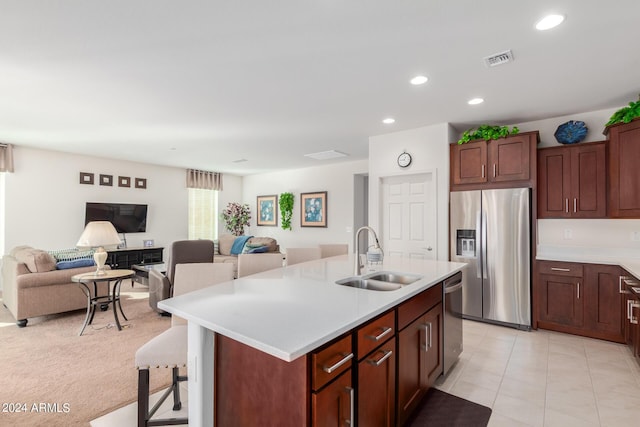 kitchen featuring light tile patterned flooring, an island with sink, sink, a kitchen breakfast bar, and stainless steel appliances