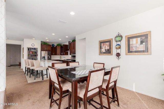 dining area with light carpet and sink