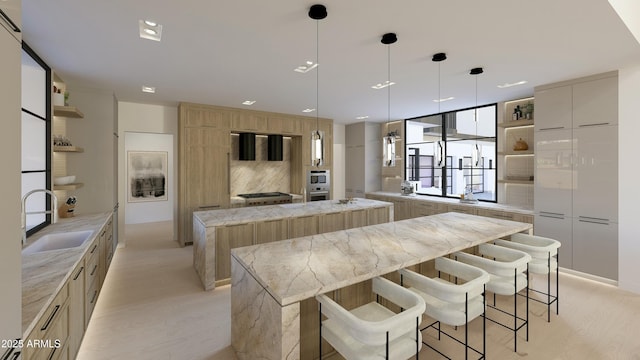 kitchen with sink, a kitchen breakfast bar, hanging light fixtures, light stone counters, and a spacious island