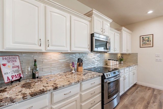 kitchen featuring white cabinetry, tasteful backsplash, light stone counters, appliances with stainless steel finishes, and light hardwood / wood-style floors