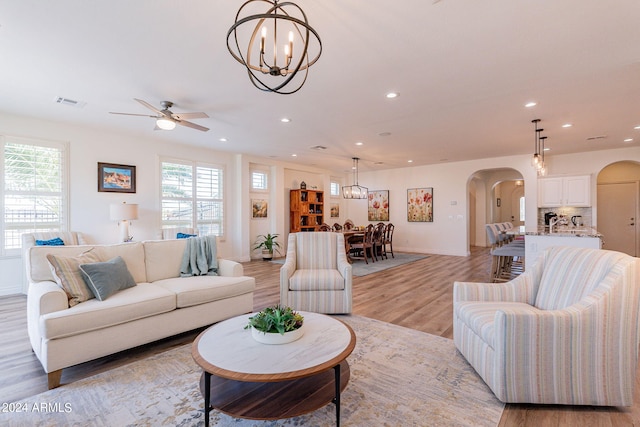 living room with plenty of natural light, ceiling fan with notable chandelier, and light hardwood / wood-style flooring