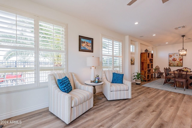 sitting room featuring hardwood / wood-style flooring and ceiling fan with notable chandelier