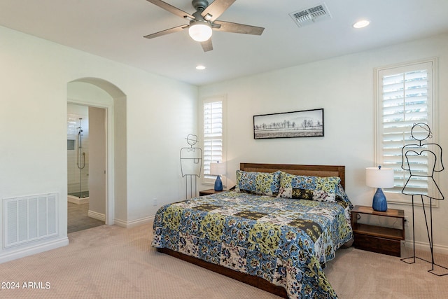 bedroom featuring multiple windows, ensuite bathroom, carpet flooring, and ceiling fan