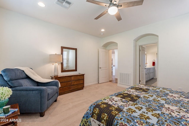 bedroom featuring light carpet, ceiling fan, and ensuite bath