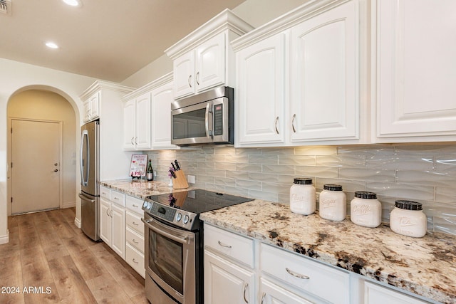 kitchen with appliances with stainless steel finishes, light stone countertops, decorative backsplash, and white cabinets