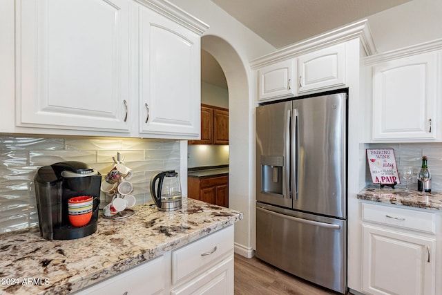 kitchen with white cabinetry, decorative backsplash, light hardwood / wood-style flooring, and stainless steel refrigerator with ice dispenser