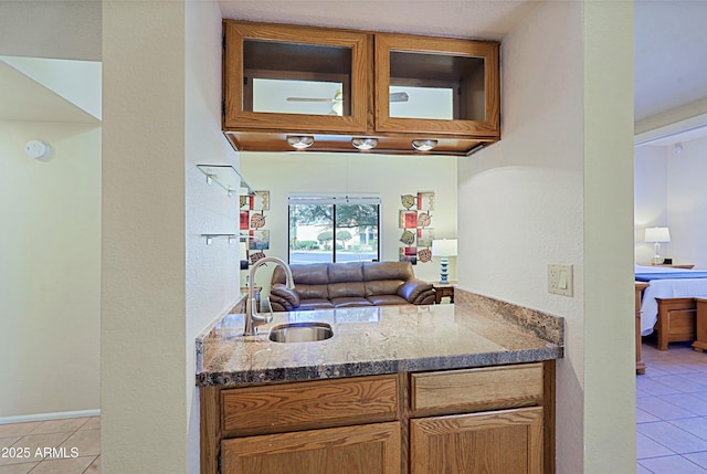 kitchen featuring dark stone countertops, sink, and light tile patterned floors