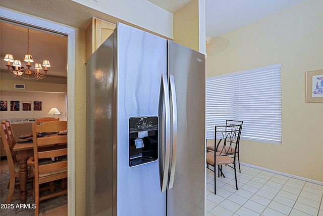 kitchen with light tile patterned floors, decorative light fixtures, stainless steel fridge, and a chandelier