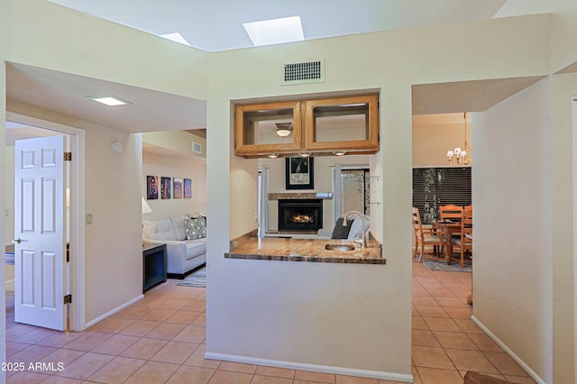 kitchen with stone countertops, decorative light fixtures, sink, a chandelier, and light tile patterned floors