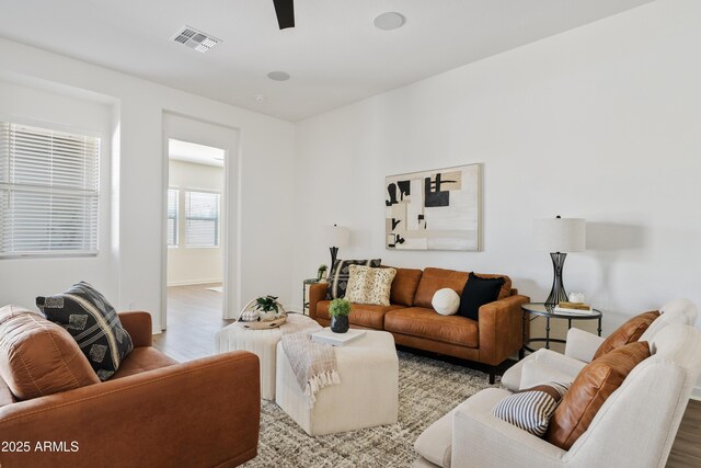 living area featuring visible vents, baseboards, ceiling fan, and wood finished floors